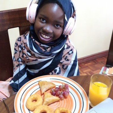 Alesta all dressed up in Swahili clothes enjoying her breakfast..jpeg